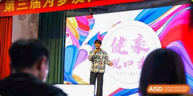 A student from The Experimental School Affiliated to Nanjing Normal University is performing on a stage with a microphone.