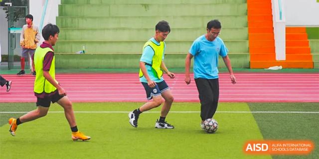 Two students from The Experimental School Affiliated to Nanjing Normal University are playing soccer on a pink-and-green field.