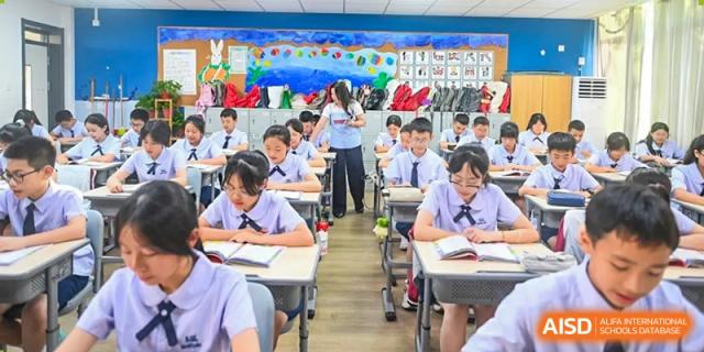 Students of Weiming School Chengdu Qingbaijiang in a classroom, with one student standing at the front.