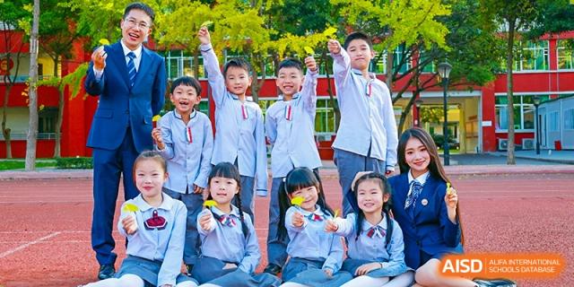 Weiming School Chengdu Qingbaijiang students pose excitedly for a group photo outdoors, celebrating with smiles and thumbs-up gestures.