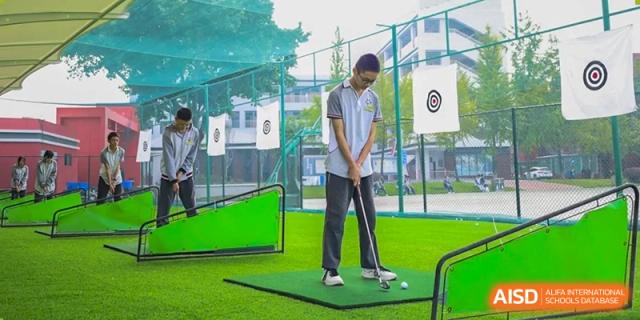 A Weiming School Chengdu Qingbaijiang student practices his golf swing at a mini-golf setup on the school grounds.