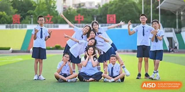 Weiming School Chengdu Qingbaijiang students in uniform posing on a grassy field.