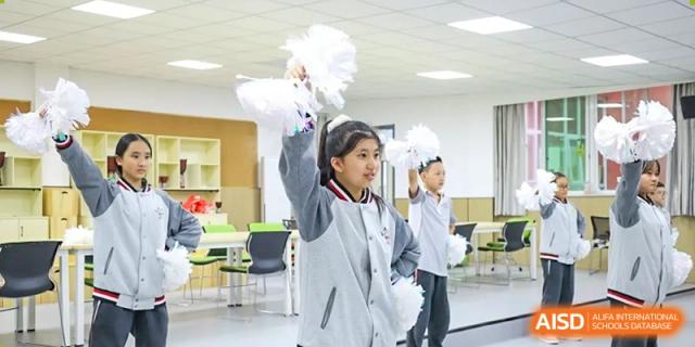 Students from Weiming School Chengdu Qingbaijiang acting as cheerleaders and holding pom-poms.
