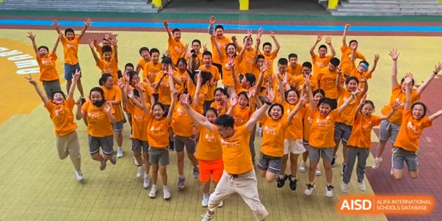 A large group of excited students from Weiming School Chengdu Qingbaijiang posing for a photo.