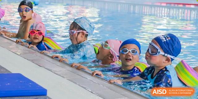 A group of smiling Weiming School Chengdu Qingbaijiang students enjoying their time in a swimming pool.
