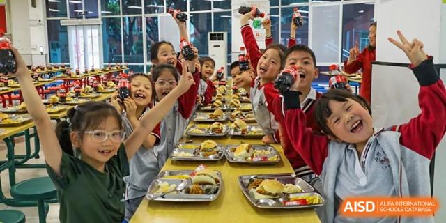 Happy students from Weiming School Chengdu Qingbaijiang enjoying a meal in the cafeteria.