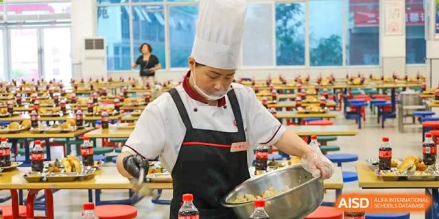 A chef serving food to students in the cafeteria at Weiming School Chengdu Qingbaijiang.