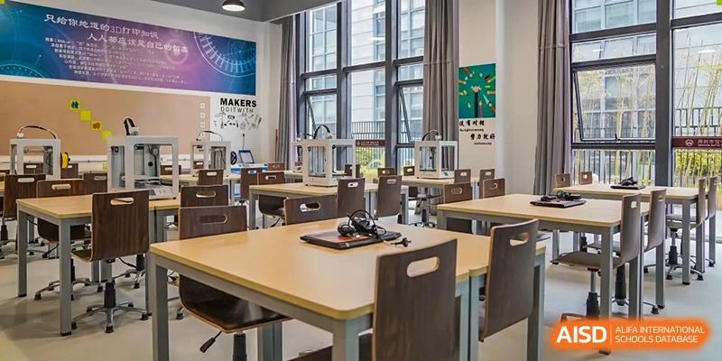 A bright, modern classroom or workshop with brown tables and chairs, viewed from a wide-angle perspective at Weiming School Shenzhen Nanshan.