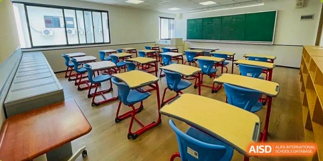 An empty classroom with colorful blue and red student desks and chairs facing a chalkboard at Weiming School Shenzhen Nanshan.