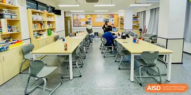 A classroom with long white tables where students are working on computers or assignments at Weiming School Shenzhen Nanshan.