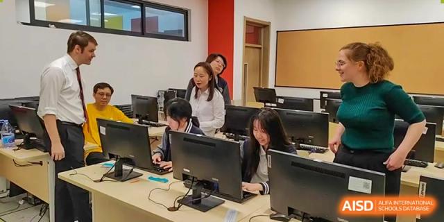 A computer lab or classroom where several female students are working on desktop computers with a teacher supervising at Weiming School Shenzhen Nanshan.