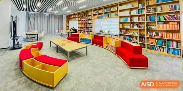 A wide view of a colorful library or reading room with low tables, circular red seating, and wall-to-wall bookshelves at Weiming School Shenzhen Nanshan.