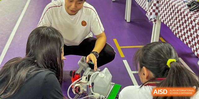 A student working on or assembling a piece of robotics or equipment while sitting on a light-colored floor at Weiming School Shenzhen Nanshan.