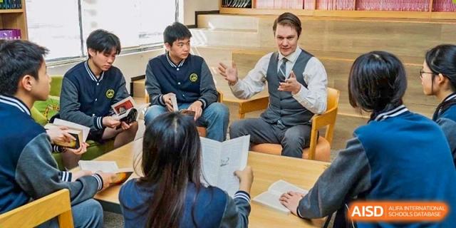 Students and a teacher or administrator having a discussion around a table in a classroom or small meeting area at Weiming School Shenzhen Nanshan.