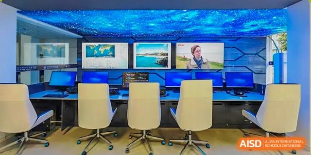 A control room or media center setup with multiple monitors displaying content, and three office chairs, at Weiming School Shenzhen Nanshan.