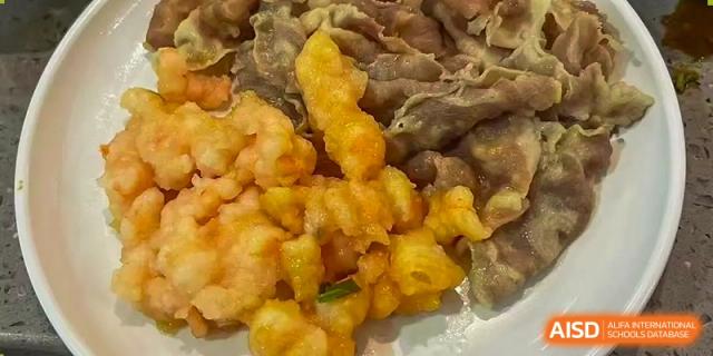 A close-up of two different appetizers or side dishes, one featuring fried meat and the other battered and fried vegetables, served at Weiming School Shenzhen Nanshan.