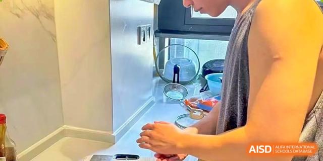 A close-up of hands pouring water into a glass in a kitchen or dining area at Weiming School Shenzhen Nanshan.
