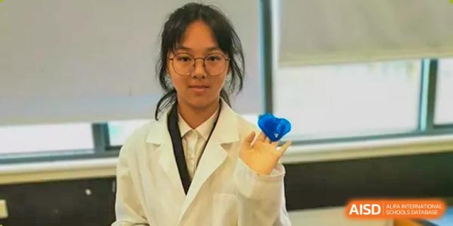 Female student in a lab coat and glasses holding a blue object at Wenzhou No.21 Middle School.