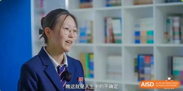 Female student smiling and speaking in front of a bookshelf at Wenzhou No.21 Middle School.