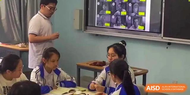 Students discussing and working at a desk in a classroom with a screen at Wenzhou No.21 Middle School.