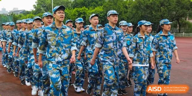 Students in camouflage military uniform marching outdoors at Wenzhou No.21 Middle School.