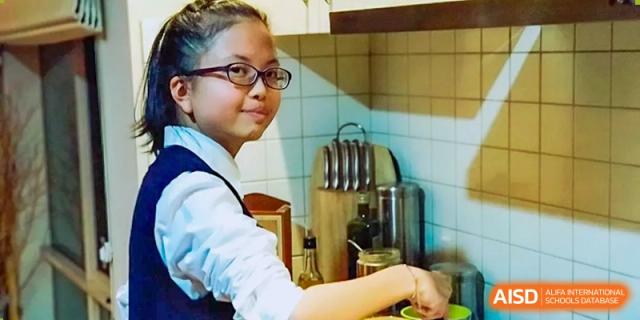 Student cooking and preparing food in a kitchen setting at Wenzhou No.21 Middle School.
