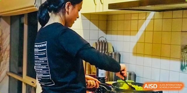 Student stirring a pot on a stovetop during a cooking activity at Wenzhou No.21 Middle School.