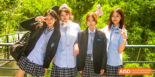 A group of three female students in school uniform posing outdoors in a bright, sunny area at Wuhan Optics Valley ULINK School.