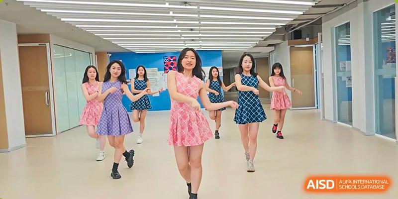 A group of female students practicing a dance routine in a bright, mirrored studio at Wuhan Optics Valley ULINK School.