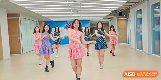 A group of female students practicing a dance routine in a bright, mirrored studio at Wuhan Optics Valley ULINK School.