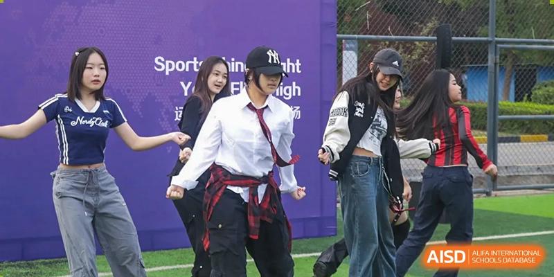 A female student dancing or performing on stage during a school event with a purple and white backdrop at Wuhan Optics Valley ULINK School.