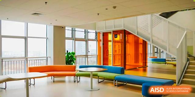 A colorful, modern student lounge or common area with orange and blue seating and large windows at Wuhan Optics Valley ULINK School.