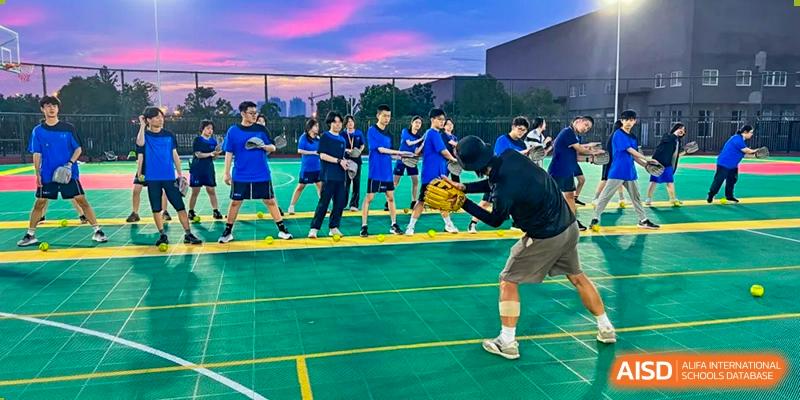 A group of male students playing basketball on an outdoor court under a vibrant sky at Wuhan Optics Valley ULINK School.