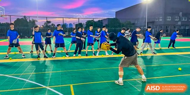 A group of male students playing basketball on an outdoor court under a vibrant sky at Wuhan Optics Valley ULINK School.