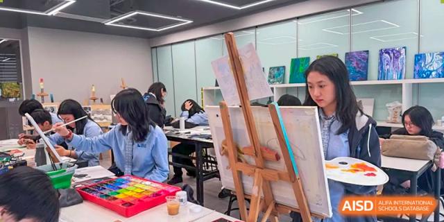 Students participating in an art class, painting on easels in a brightly lit studio at Wuhan Optics Valley ULINK School.