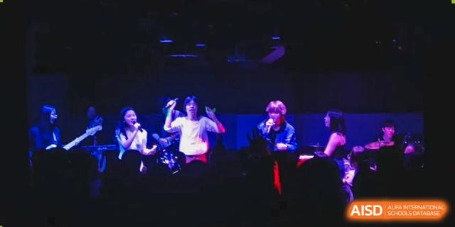 Two students performing as a band on a dimly lit stage during a school music event or concert at Wuhan Optics Valley ULINK School.
