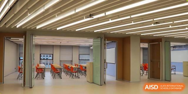 A clean, open classroom with orange and white chairs and a collapsible glass partition wall at Wuhan Optics Valley ULINK School.