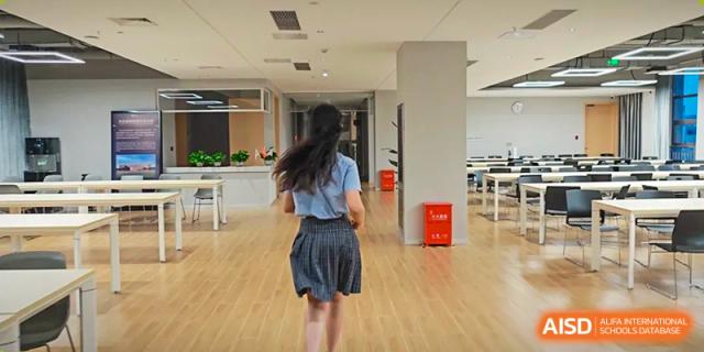 A female student in school uniform running down a bright, modern hallway with wooden floors at Wuhan Optics Valley ULINK School.