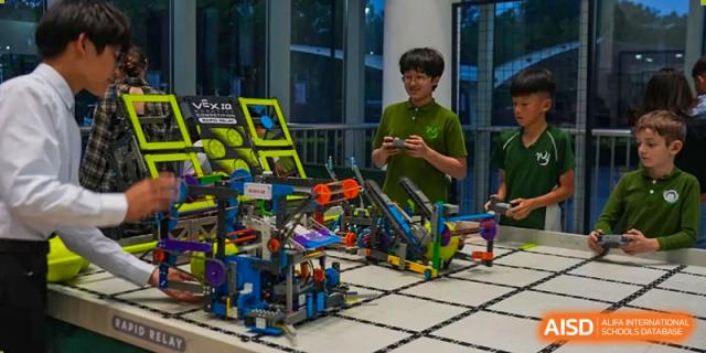 A Wuhan Yangtze International School student uses a remote control to operate a complex, custom-built robot during a robotics competition.