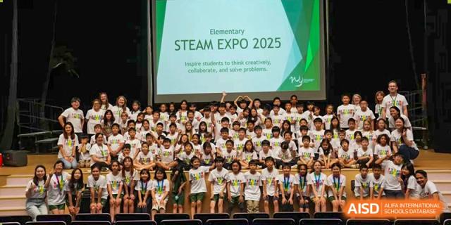 A large group of smiling Wuhan Yangtze International School elementary students seated together in front of a screen displaying "Elementary STEAM EXPO 2025."