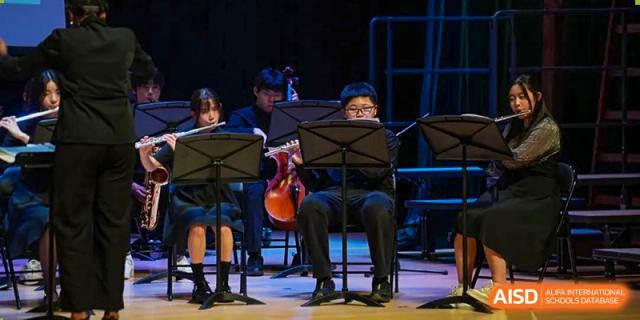 A close-up of several Wuhan Yangtze International School students performing on string instruments in a school band or orchestra concert.