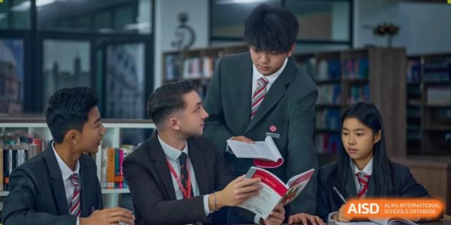 A male teacher in a black suit discussing a textbook or assignment with a male student in uniform at Wuxi Dipont School of Arts and Science.
