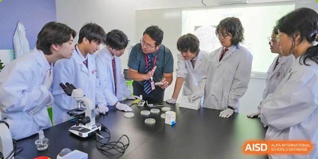 A group of students in lab coats gathered around a table examining petri dishes and conducting an experiment at Wuxi Dipont School of Arts and Science.