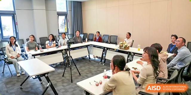 A wide shot of a small, formal meeting or conference taking place with adults seated around a large table at Wuxi Dipont School of Arts and Science.