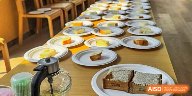 A table covered with many white plates, each containing slices of cake or pastry, set out for an event or meal at Wuxi Dipont School of Arts and Science.