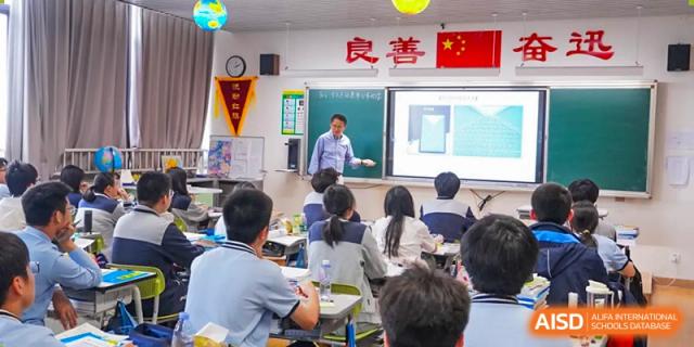 A teacher instructing a classroom full of students, with a Chinese flag displayed, at Wuxi Kuangyuan Bilingual School.