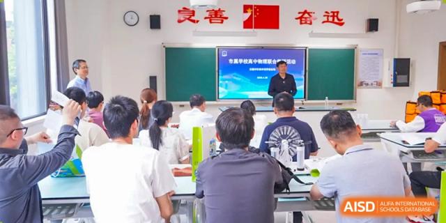 A view from the back of the classroom showing a teacher presenting at a blackboard or screen to seated students at Wuxi Kuangyuan Bilingual School.