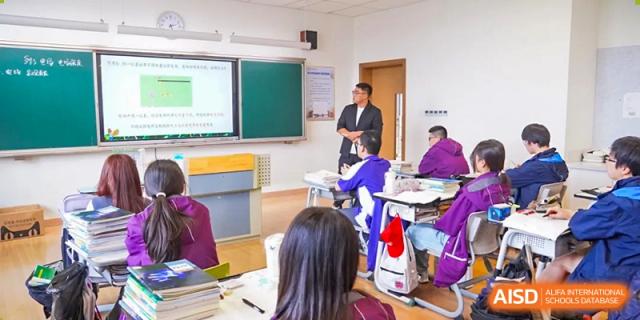 A teacher standing and lecturing to a classroom of seated students during a lesson at Wuxi Kuangyuan Bilingual School.