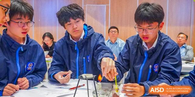 A male student carefully heating a substance with a lab burner during a chemistry experiment in a science lab at Wuxi Kuangyuan Bilingual School.