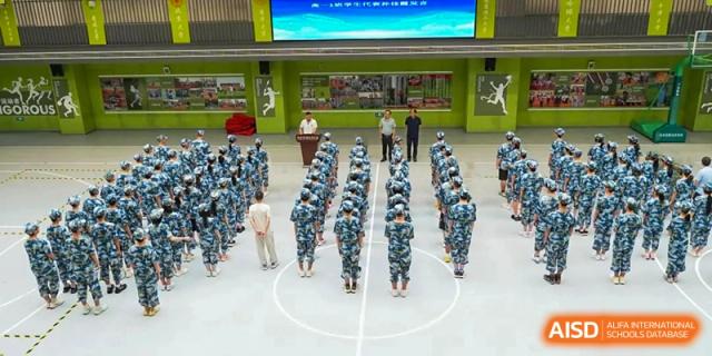 Students dressed in camouflage uniforms standing in formation on an outdoor court for a military training or assembly at Wuxi Kuangyuan Bilingual School.